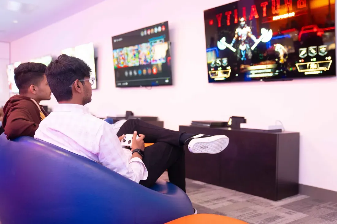 Two students in Esports room playing game on television.